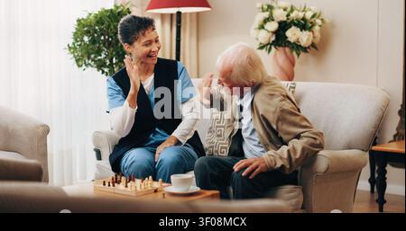 Happy, Krankenschwester und High Five mit Senior-Mann für Schach, Brettspiel oder gemeinsam zu Hause gewinnen. Frau, medizinisches Fachpersonal oder Pflegekraft, die mit einem Lächeln spielt Stockfoto