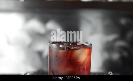 Glas mit eiskaltem roten Cocktail auf einer Theke, erfrischendes kaltes Getränk für eine Party oder Feier Stockfoto