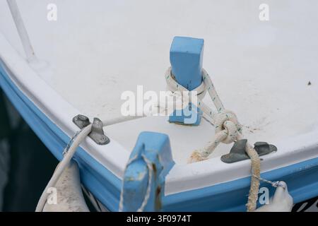 Seil an einem blauen Pfosten festgebunden, sicher befestigt, auf einem Bootsdeck, mit blauem Pfosten, weißem Seil, Bootsdeck, mit Plastik, Baumwolltextur, aus einer Nahaufnahme von oben Stockfoto