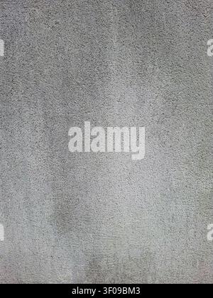 Die Oberfläche weist eine raue, unebene Textur mit Anzeichen von Abnutzung auf und zeigt eine gedämpfte graue Farbe. Diese Betonwand spiegelt ihre Exposition gegenüber den Elementen wider Stockfoto