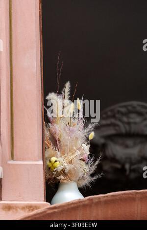 Getrocknetes Blumenarrangement in einer Keramikvase auf einer rustikalen Fensterbank ausgestellt Stockfoto