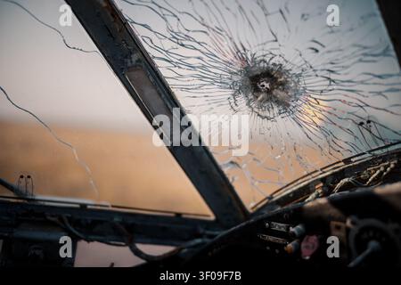 Ansicht aus einem verlassenen Flugzeugcockpit mit einem Einschussloch und einer zerschmetterten Windschutzscheibe mit Spinnennetzrisse. Stockfoto