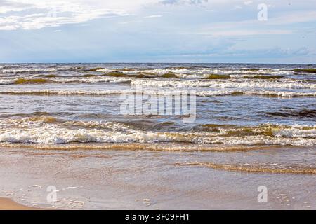 Wellen im Golf von Riga, als die Sonne an einem verlassenen Strand von Jurmala hervorschaute Stockfoto