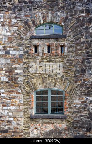 Historische Steingebäudefassade mit gewölbten Fenstern und rustikaler Mauertextur Stockfoto