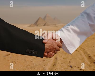 Ein fester Geschäftsgebrauch zwischen einem Mann in einem schwarzen Anzug und einem arabischen Mann in einem weißen Kandura vor den Pyramiden von Gizeh. Symbolisiert Vertrauenspartnerschaft und Cross-Cultural Investment Deals. - Fotomontage Stockfoto