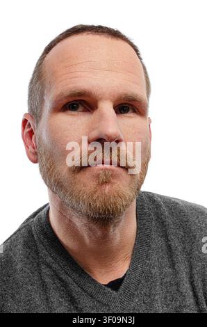 Ein Porträt eines ernsthaften Mannes mittleren Alters mit Bart und Schnurrbart, der einen grauen Pullover vor weißem Hintergrund trägt. Stockfoto