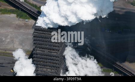 Luftaufnahme der Kokerei Schwelgern mit dickem weißem Dampf, der aus dem Industriegebäude steigt, umgeben von Eisenbahngleisen in Duisburg, Stockfoto