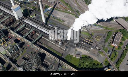 Aus der Vogelperspektive des Industriekomplexes Kokerei Schwelgern KBS thyssenkrupp Steel mit Rauch aus einem Kokerei-Turm, Eisenbahngleisen und Infrastruktur in Duis Stockfoto