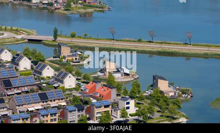 Blick aus der Vogelperspektive auf moderne Wohnhäuser mit Solarpaneelen entlang eines Kanals in Heerhugowaard, Nordholland, Niederlande. Stockfoto