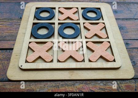 Vintage-Holztisch Tic-Tac-Toe-Brett auf rustikalem Holztisch zeigt Gewinnmuster. Nahaufnahme-Strategiespielkonzept mit natürlicher Textur. Stockfoto