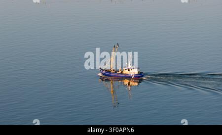 Aus der Vogelperspektive des niederländischen Garnelenfischers ST28 Lubbert Senior, das während des Sonnenuntergangs in der goldenen Stunde den Hafen Stavoren in Friesland verlässt. Stockfoto