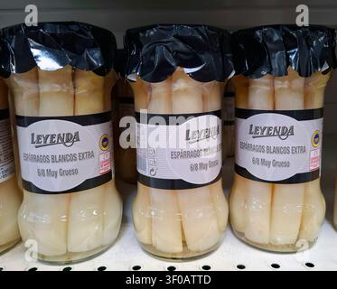 DENIA, SPANIEN - 11. Oktober 2025. Gläser gefüllt mit eingelegtem Spargel säumen ein Regal in einem spanischen Geschäft und heben beliebte lokale Delikatessen hervor, die für Stockfoto