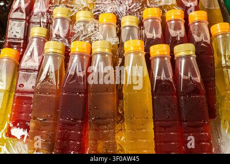 Plastikflaschen mit thailändischem Chrysanthemen-Tee und Hibiskus-Saft, gekühlt in zermahlenem Eis auf einem traditionellen Straßenmarkt in Thailand. Stockfoto