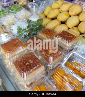 Traditionelle thailändische Desserts, verpackt in klaren Plastikbehältern, die zum Verkauf auf einem lokalen Straßenmarkt ausgestellt sind. Stockfoto