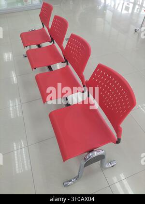 Perspektivische Ansicht von roten Plastikstühlen in einem leeren Wartebereich oder Terminal. Stockfoto