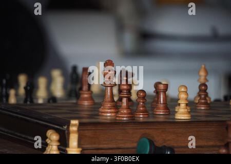 Eine Seitenansicht eines aufgestellten Holzschachbretts mit allen klassischen Figuren an ihrem Platz. Die geringe Tiefenschärfe erzeugt eine weiche Hintergrundunschärfe, hoch Stockfoto