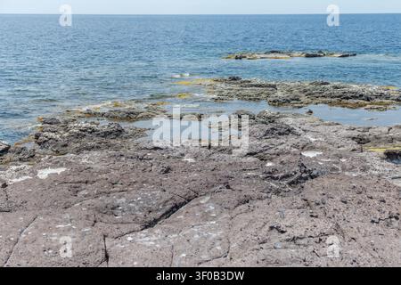 Landschaft mit felsiger Küste in blauem Wasser an der Mittelmeerküste nahe Calasetta, aufgenommen im hellen Frühlingslicht auf der Insel Sant Antioco, Cagliari, Italien Stockfoto