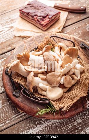 Frisch geerntete Austernpilze und gepökelter Schweinebauch auf einem rustikalen Holztisch Stockfoto