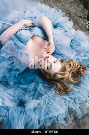 Blonde Frau in einem fließenden blauen Kleid. Stockfoto