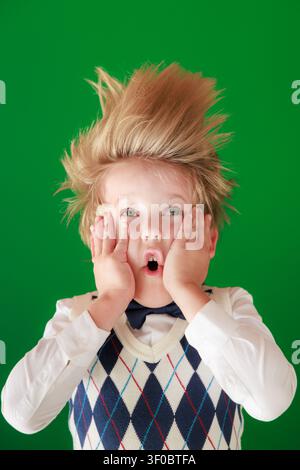 Überraschtes Kind im Unterricht. Lustiges Kind vor grüner Kreidetafel. Zurück zur Schule und Bildungsbegriff Stockfoto
