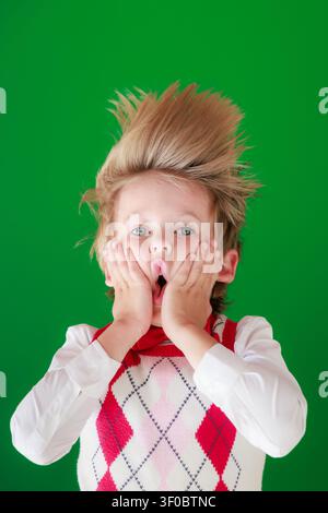 Überraschtes Kind im Unterricht. Lustiges Kind vor grüner Kreidetafel. Zurück zur Schule und Bildungsbegriff Stockfoto