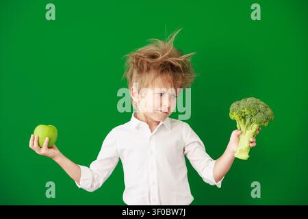 Überraschtes Kind im Unterricht. Lustiges Kind vor grüner Kreidetafel. Zurück zur Schule und Bildungsbegriff Stockfoto