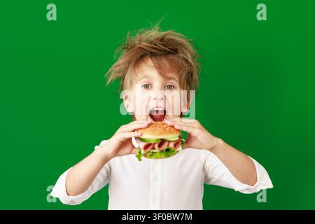 Überraschtes Kind im Unterricht. Lustiges Kind vor grüner Kreidetafel. Zurück zur Schule und Bildungsbegriff Stockfoto