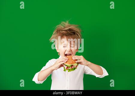 Überraschtes Kind im Unterricht. Lustiges Kind vor grüner Kreidetafel. Zurück zur Schule und Bildungsbegriff Stockfoto