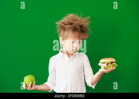 Überraschtes Kind im Unterricht. Lustiges Kind vor grüner Kreidetafel. Zurück zur Schule und Bildungsbegriff Stockfoto