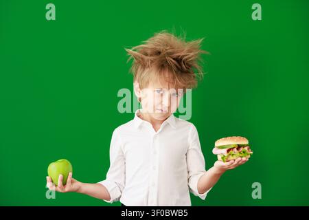 Überraschtes Kind im Unterricht. Lustiges Kind vor grüner Kreidetafel. Zurück zur Schule und Bildungsbegriff Stockfoto
