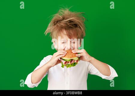 Überraschtes Kind im Unterricht. Lustiges Kind vor grüner Kreidetafel. Zurück zur Schule und Bildungsbegriff Stockfoto