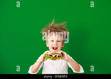 Überraschtes Kind im Unterricht. Lustiges Kind vor grüner Kreidetafel. Zurück zur Schule und Bildungsbegriff Stockfoto