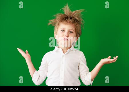 Überraschtes Kind im Unterricht. Lustiges Kind vor grüner Kreidetafel. Zurück zur Schule und Bildungsbegriff Stockfoto