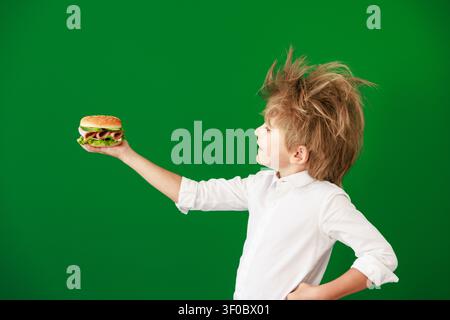 Überraschtes Kind im Unterricht. Lustiges Kind vor grüner Kreidetafel. Zurück zur Schule und Bildungsbegriff Stockfoto
