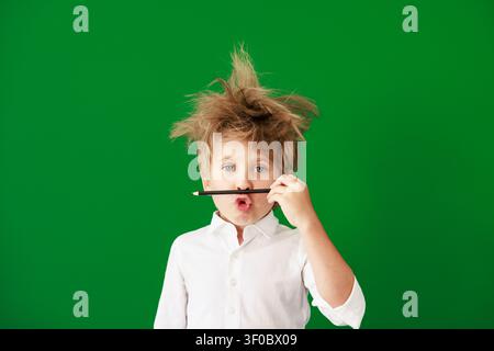 Überraschtes Kind im Unterricht. Lustiges Kind vor grüner Kreidetafel. Zurück zur Schule und Bildungsbegriff Stockfoto
