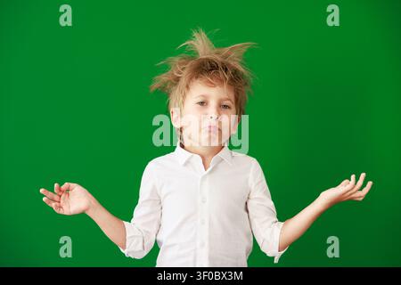 Überraschtes Kind im Unterricht. Lustiges Kind vor grüner Kreidetafel. Zurück zur Schule und Bildungsbegriff Stockfoto