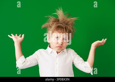 Überraschtes Kind im Unterricht. Lustiges Kind vor grüner Kreidetafel. Zurück zur Schule und Bildungsbegriff Stockfoto