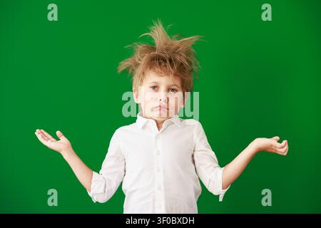 Überraschtes Kind im Unterricht. Lustiges Kind vor grüner Kreidetafel. Zurück zur Schule und Bildungsbegriff Stockfoto