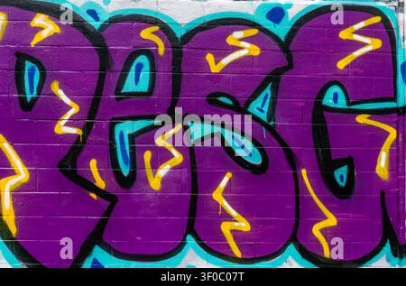 Lebendige Nahaufnahme eines lila Graffiti-Murals, das auf einer Ziegelwand gemalt ist, mit kräftigen schwarzen Konturen und hellen türkisen und gelben Akzenten. Urbane Straßenkunst Stockfoto