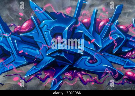 Auffällige Nahaufnahme eines futuristischen Graffiti-Murals mit dynamischen blauen abstrakten Buchstaben und lebhaften pinken Neonakzenten auf einer strukturierten Wand. Das Kunstwerk Stockfoto