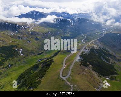 Serpentinenzufahrten schlängeln sich durch grüne Berglandschaft unter wolkigem Himmel, Luftaufnahme, nahe Ranca, Ranca, Transalpina-Hochstraße, Drum national 67C Stockfoto