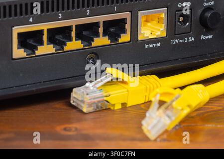 Gelbes Ethernet-Kabel, das an einen Netzwerkrouter-Anschluss angeschlossen ist, Nahaufnahme. Stockfoto