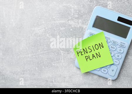Klebezettel mit den Worten Rentenplan und Taschenrechner auf grauem Tisch, Ansicht von oben. Platz für Text Stockfoto