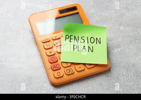 Klebezettel mit den Worten Rentenplan und Taschenrechner auf grauem Tisch, Nahaufnahme Stockfoto