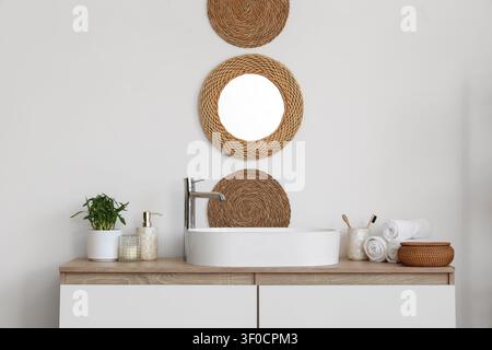 Modernes Waschbecken im Bad mit Korbspiegel und Accessoires Stockfoto