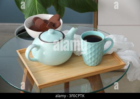 Tee-Set mit Tasse und herzförmigen Keksen auf Glastisch Stockfoto