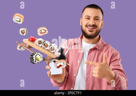 Lächelnder Mann, der auf Sushi-Lieferung auf dem Smartphone zeigt Stockfoto