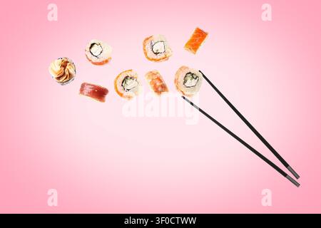 Verschiedene Sushi-Stücke mit Stäbchen auf rosafarbenem Hintergrund Stockfoto