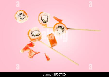 Sushi-Brötchen mit Stäbchen und Ingwer auf rosa Hintergrund Stockfoto