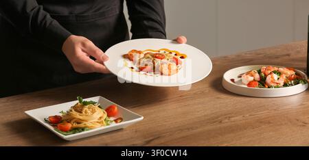 Der Koch serviert Garnelen-Pastagerichte auf Holztisch Stockfoto